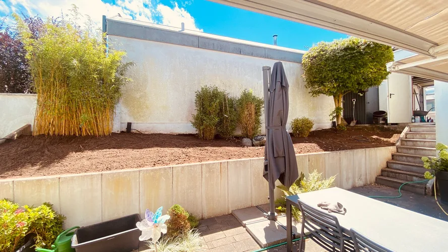 Neu angelegtes Beet mit frischem Rindenmulch neben einer Terrasse