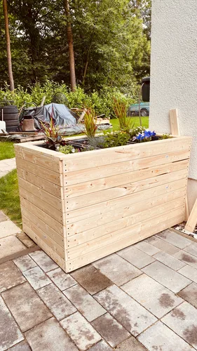 Hochbeet aus Holz auf einer gepflasterten Fläche
